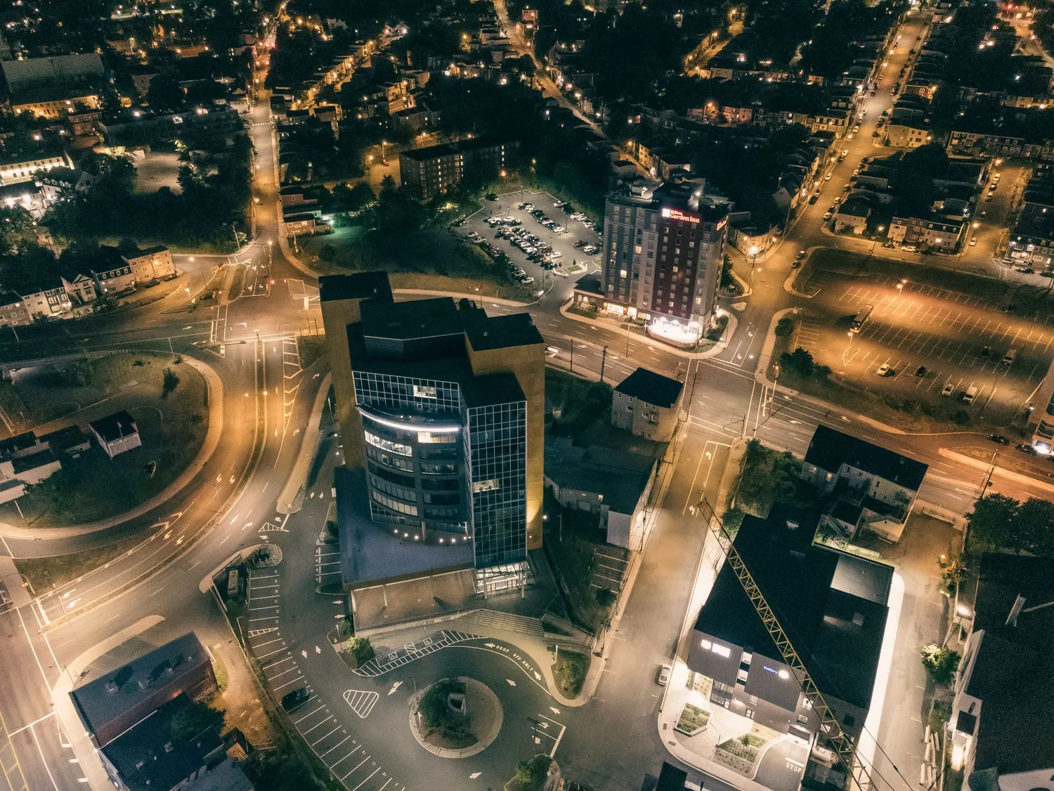 Vista aérea nocturna de una ciudad con calles, cruces y edificios iluminados.