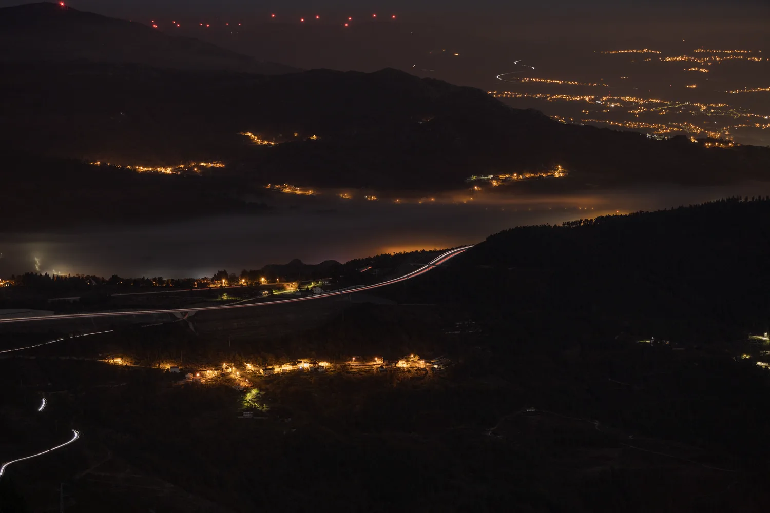 Vista aérea nocturna de infraestructura vial y luces trazando el recorrido de una carretera.